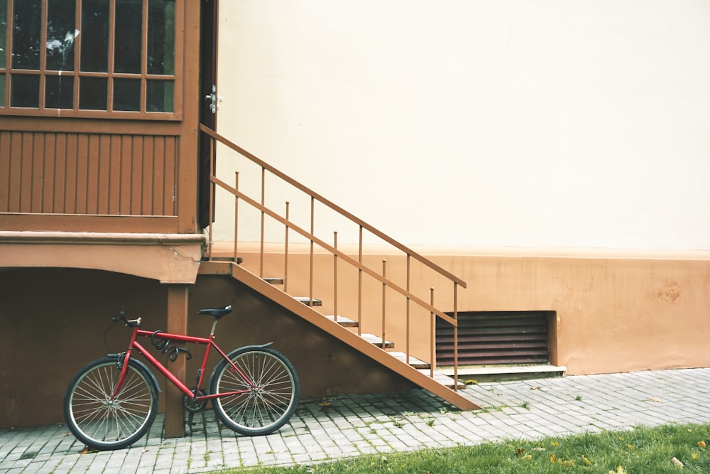 red bicycle parked beside house