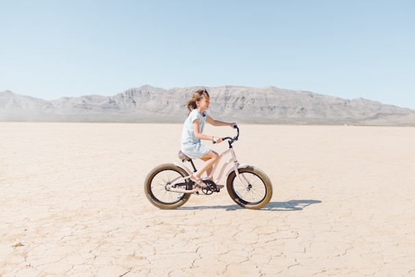 A biker riding through a vast desert landscape under a clear blue sky.