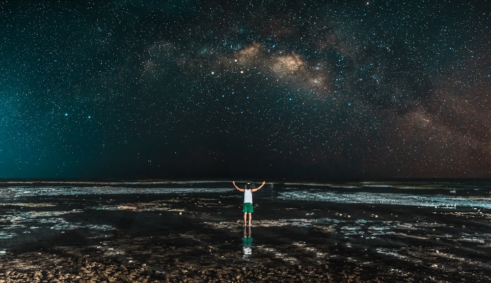 person standing in front of sea during nighttime