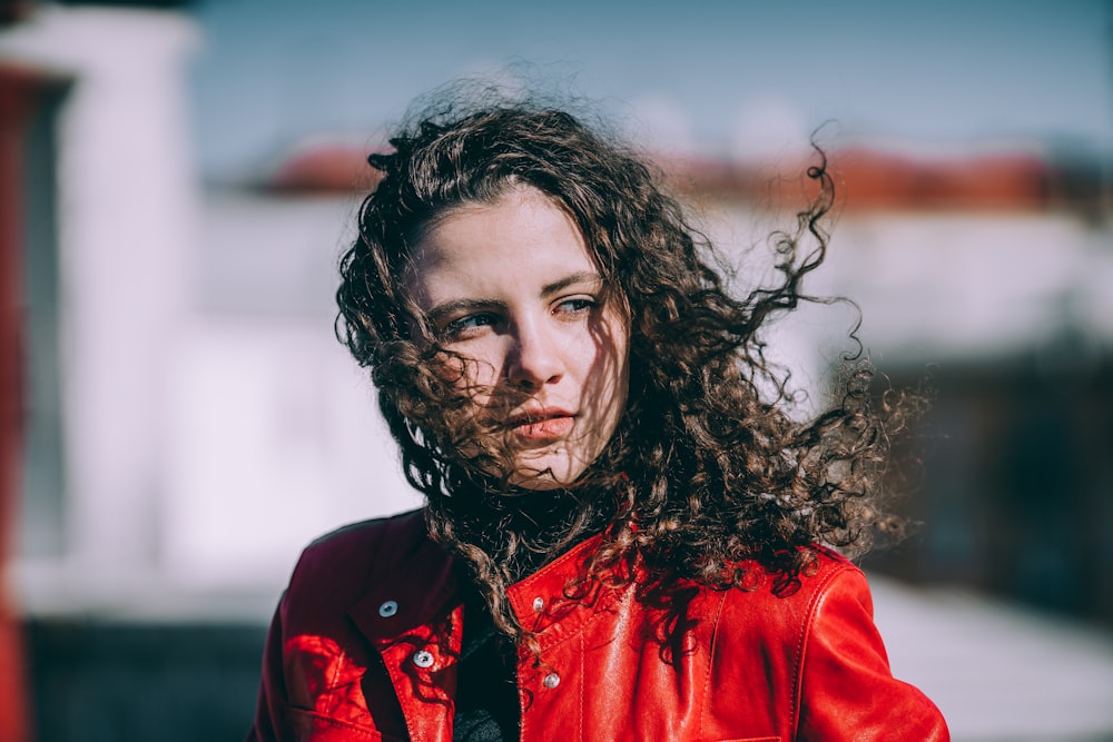 woman in red jacket standing outside during daytime