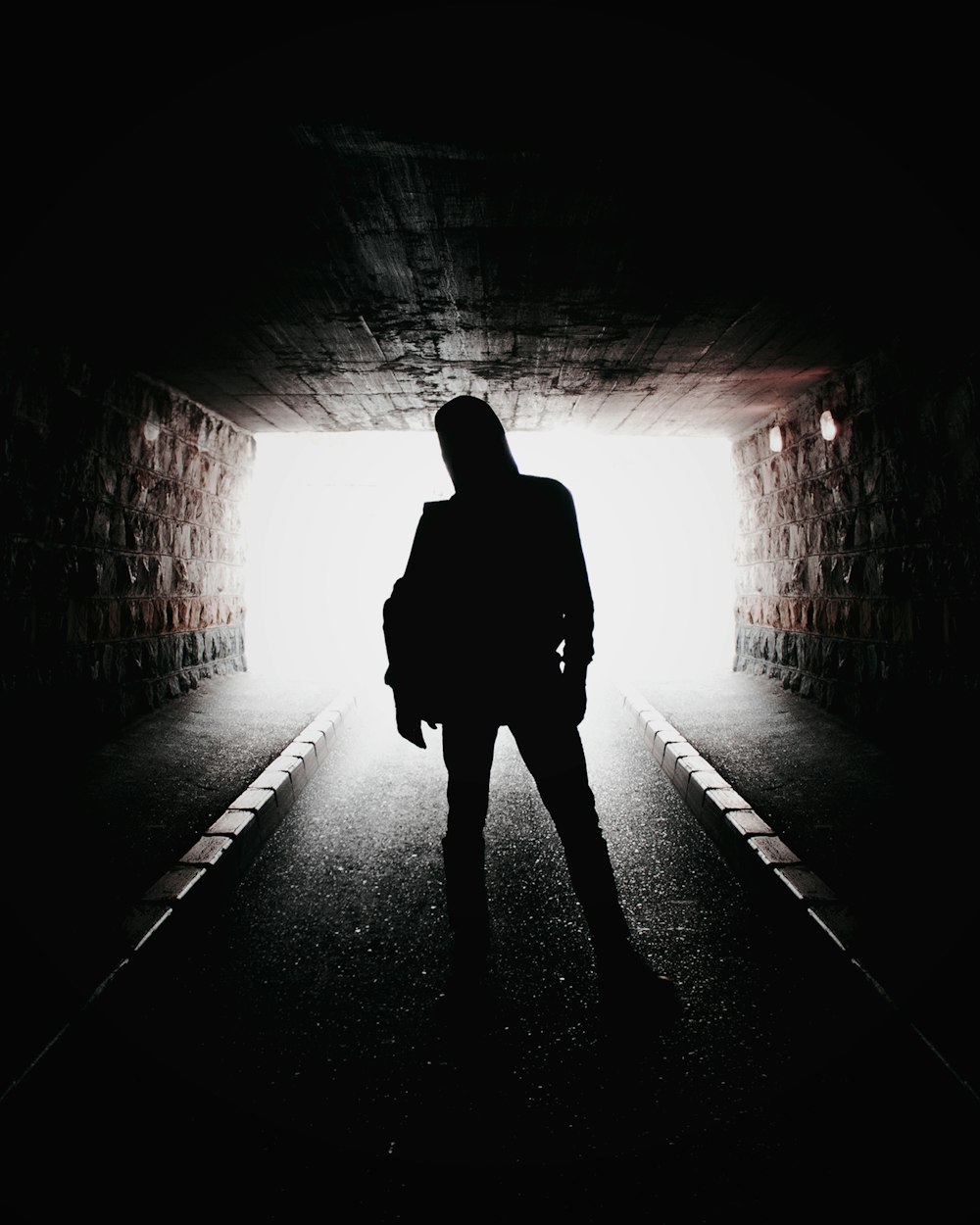silhouette of man standing in tunnel