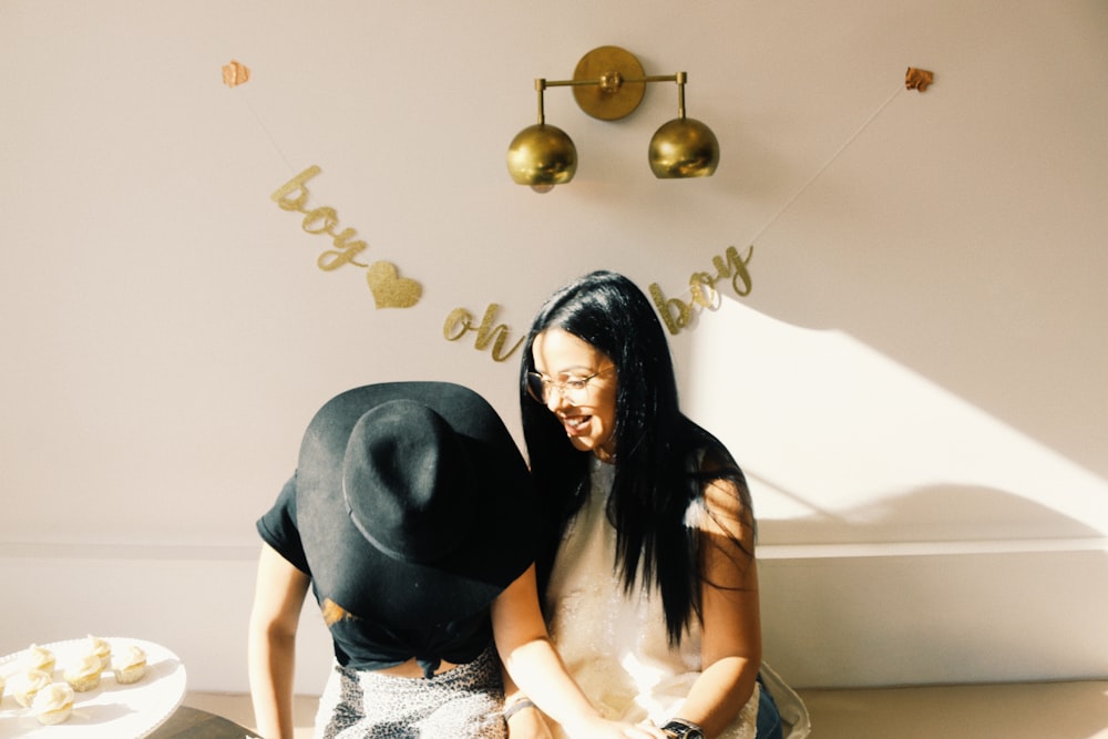 smiling woman sitting beside person wearing black hat