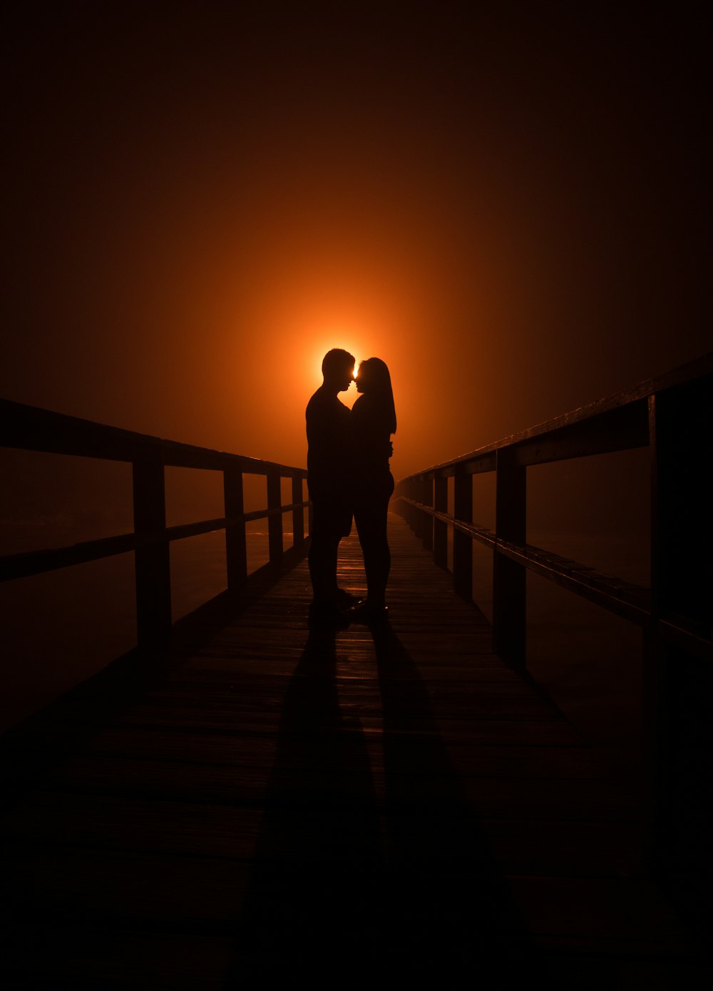 silhouette of man and woman standing on dock during susnet