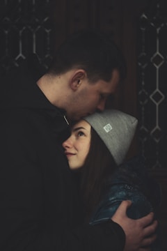 man kissing woman's forehead