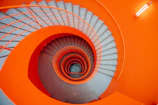 Close-up of a stairwell painted in vibrant orange with clean lines and sharp edges.