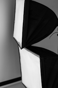 Two softbox lights with a black exterior and white diffusing surface. They are positioned at an angle against a neutral background.