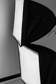 Two softbox lights with a black exterior and white diffusing surface. They are positioned at an angle against a neutral background.