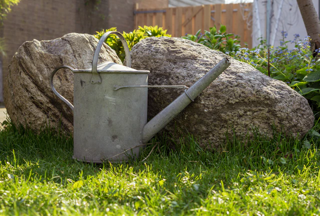A sleek, modern watering can resting on a wooden garden bench with morning sunlight.