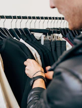 Close-up of hands browsing through a selection of quality used clothing on a rack.