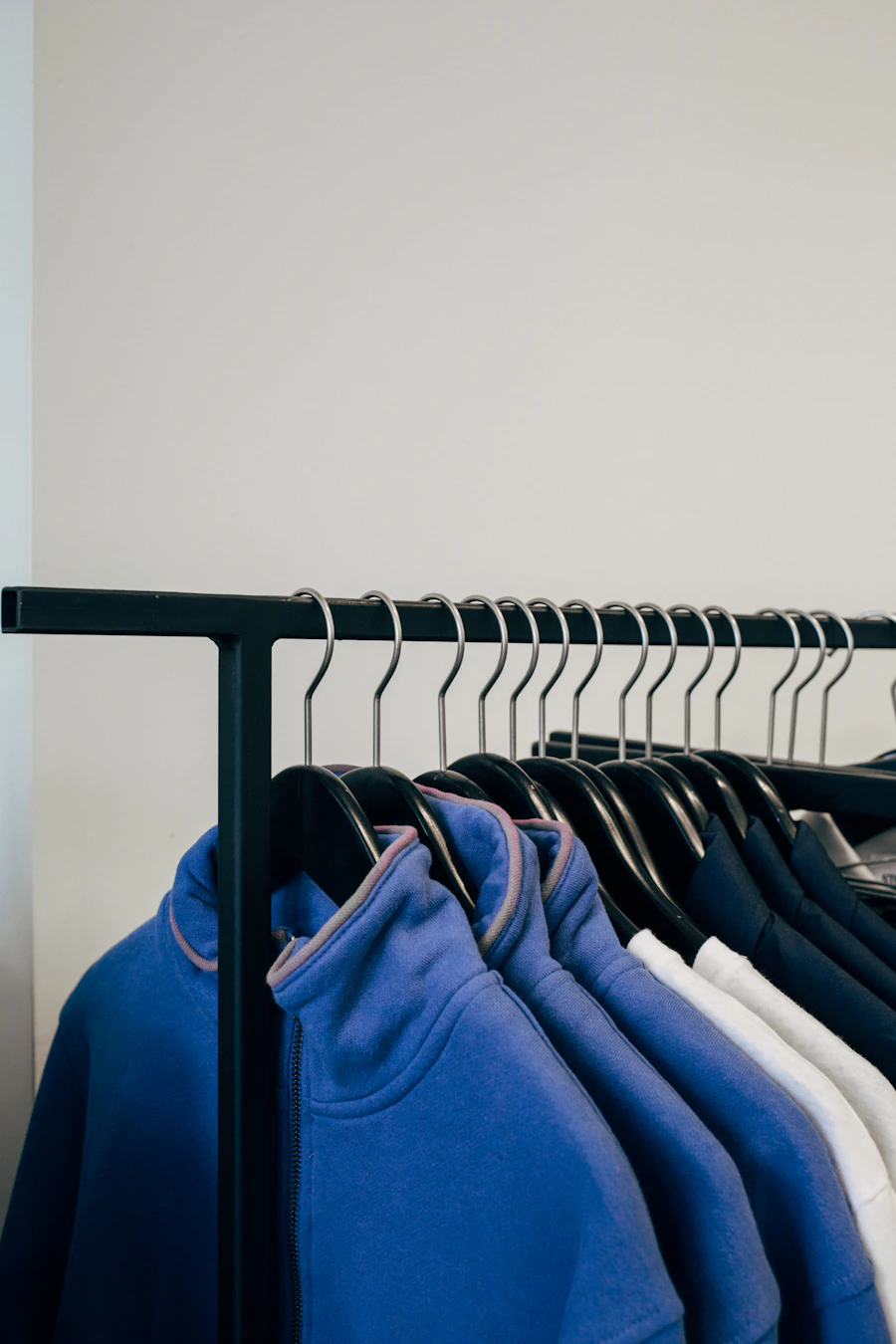 Blue zip fleeces hanging on a black clothes rail
