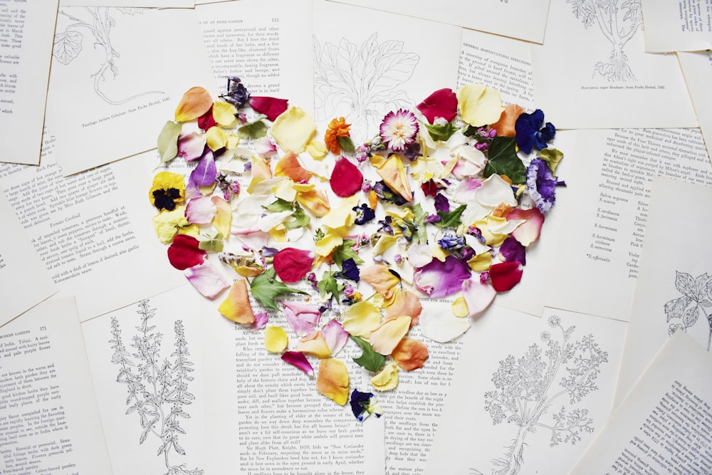 a heart made out of flowers sitting on top of an open book