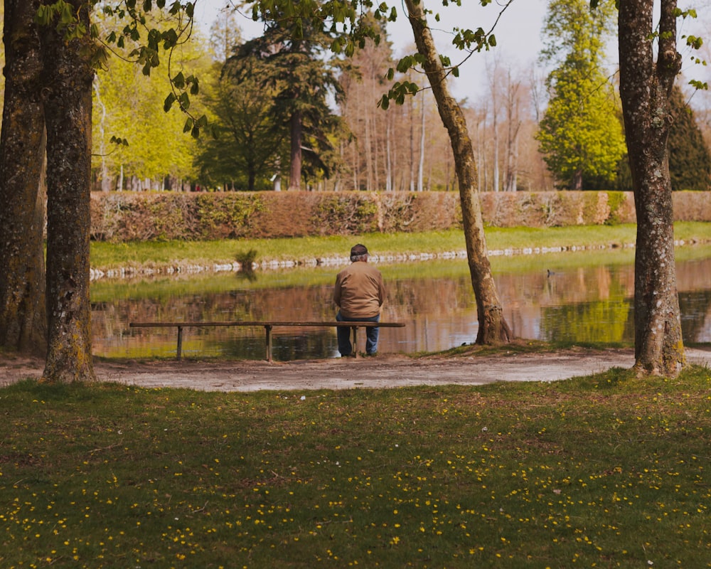man sitting on bench near lake