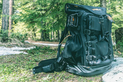 A rugged backpack filled with essential survival gear in a forest setting.