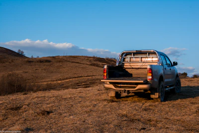 A rugged pickup truck parked beside an open highway under a wide, open sky at sunset.