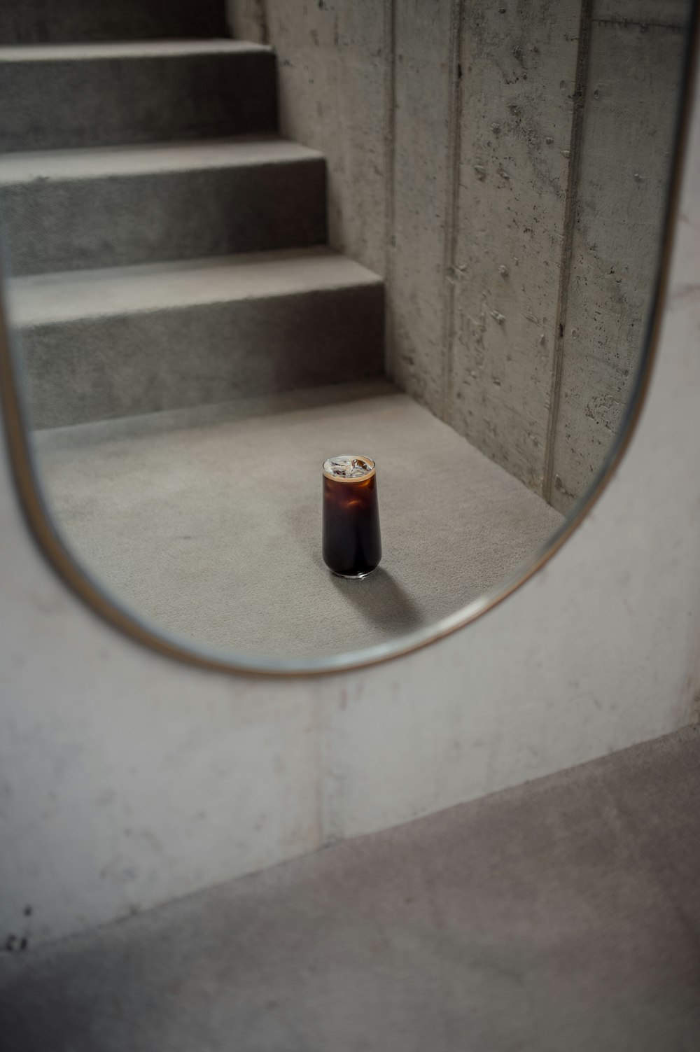 a bottle of beer sitting on the ground in front of a mirror