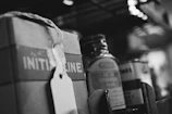 Monochrome shot of vintage perfume bottles lined up on a wooden shelf.