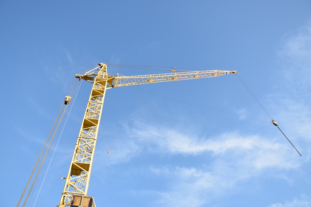 a yellow crane is in the middle of a blue sky