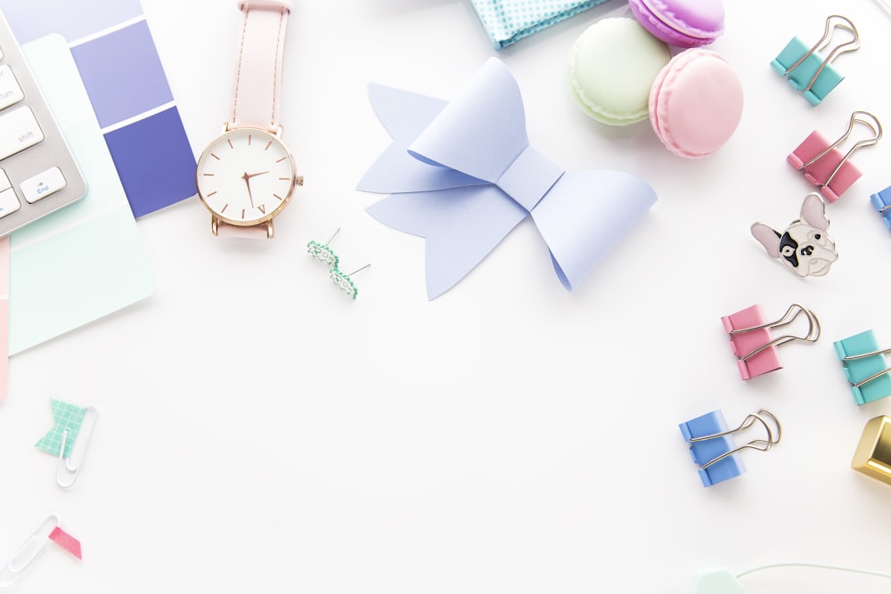 round white and gold-colored analog watch beside paper ribbon