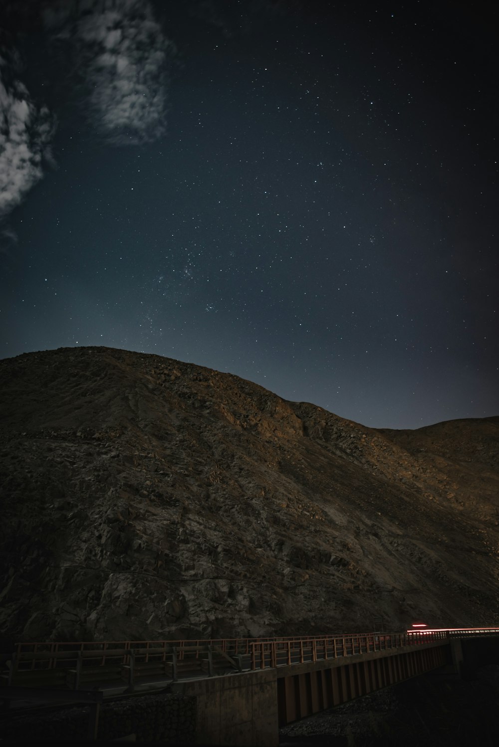 the night sky over a mountain and a bridge