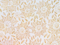 A decorative floral motif painted with delicate brush strokes on a light background.