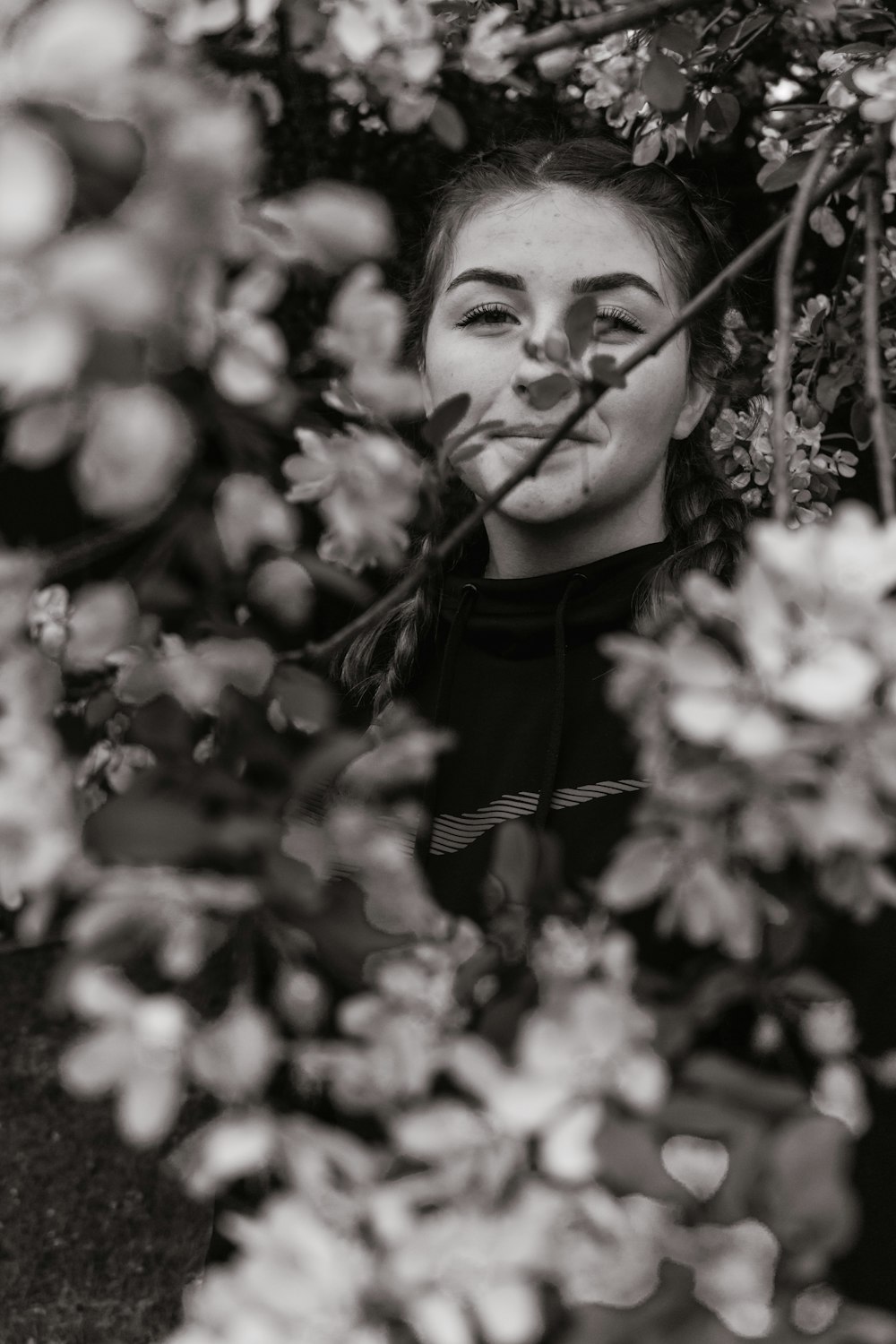 grayscale photo of woman behind plant