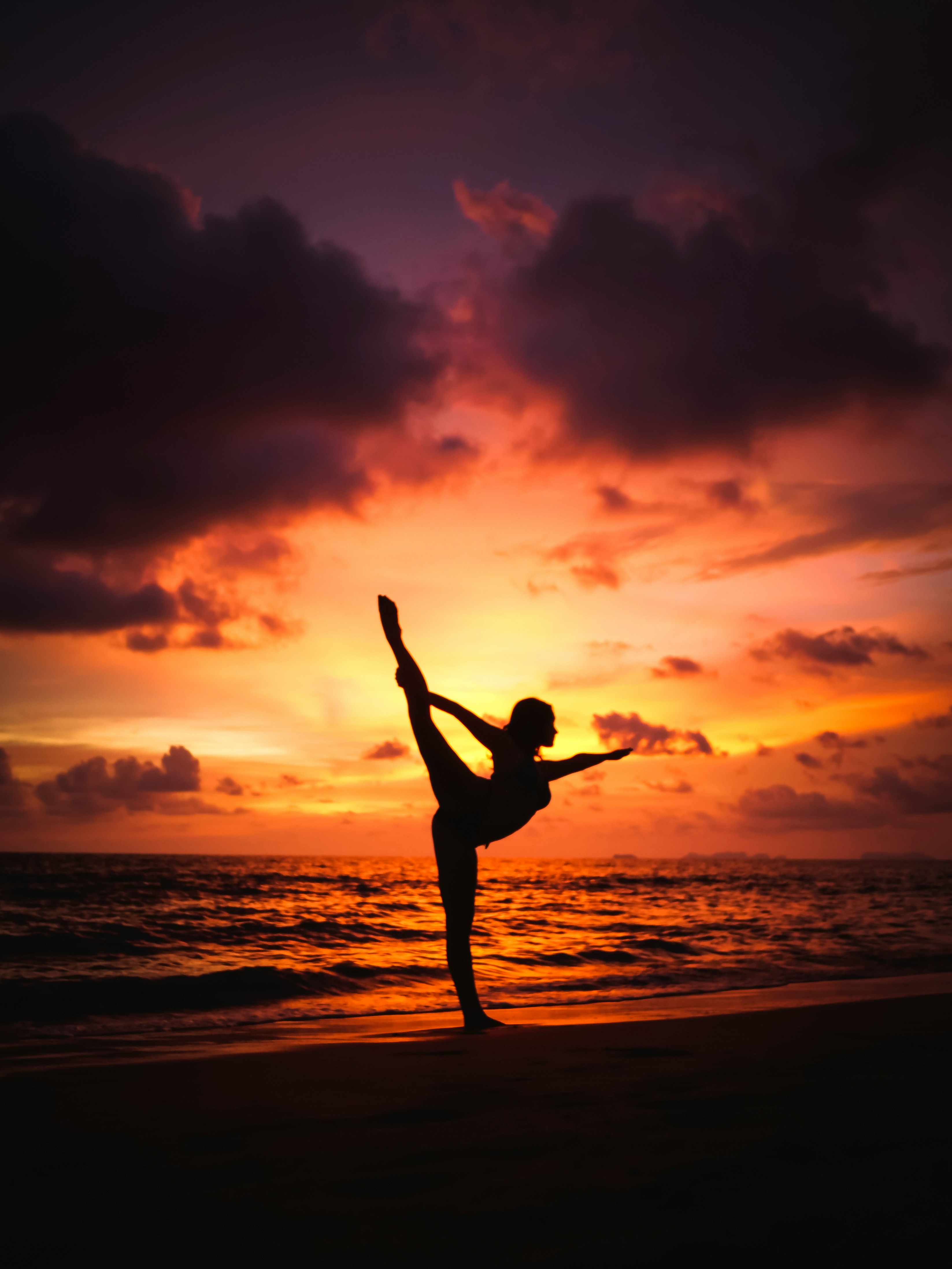 silhouette photography of woman stretching front of sea