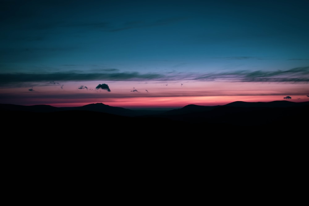 the sun is setting over a mountain range