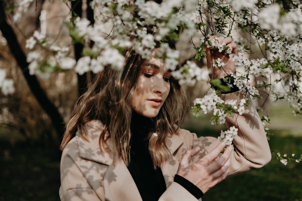 woman wearing brown suit jacket beside white flower