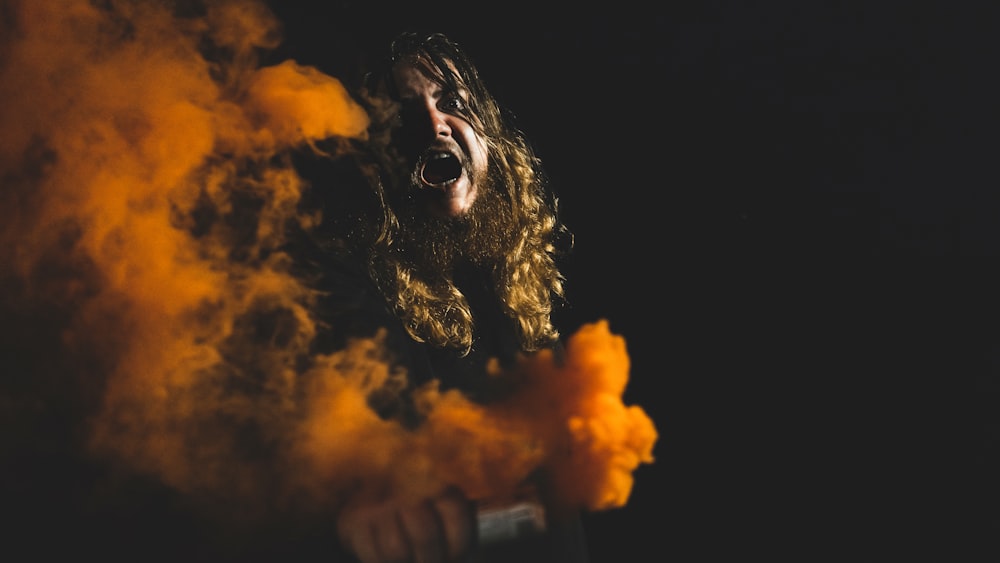 man holding orange smoke can