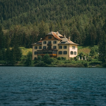 A cozy house by the lake with a 'For Sale' sign in front