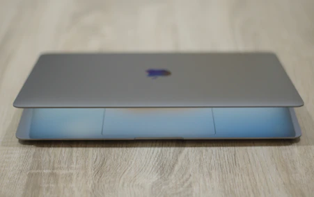 Sleek laptop opened on a wooden desk with soft natural lighting highlighting its slim design.