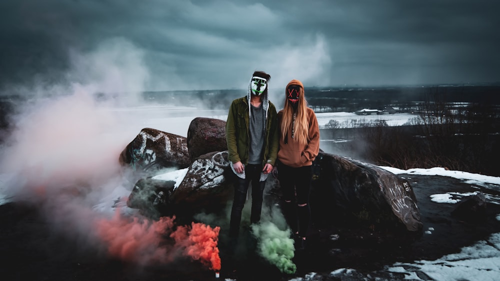 man and woman standing near rock boulder