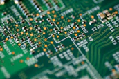Close-up of a circuit board with green leaves growing around it symbolizing tech and nature.