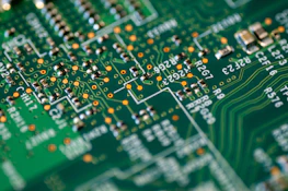 Close-up of a circuit board with green leaves growing around it symbolizing tech and nature.