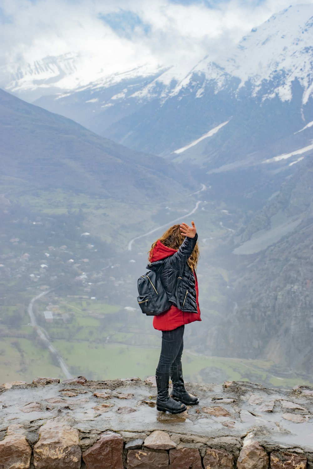 Mujer de pie sobre la roca levantando su mano derecha