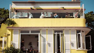 The two-story structure of Ozzy Cafe Bar with fans gathered on the balcony.