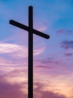 A cross silhouetted against a colorful sunset sky, symbolizing hope and redemption.