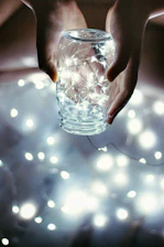 Hands gently holding a small donation jar with a warm, glowing background.