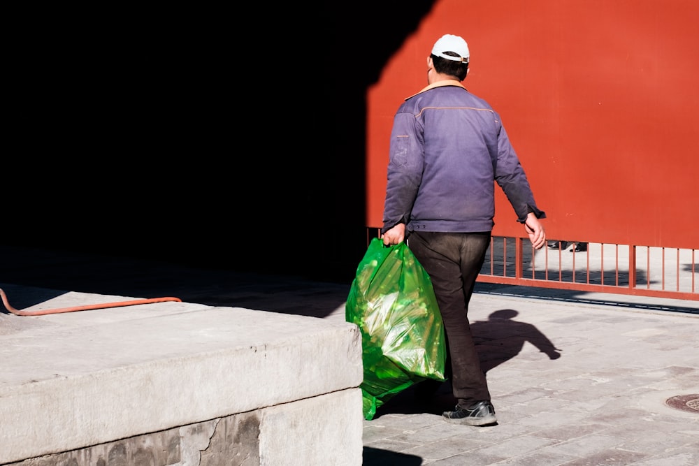 homme portant un sac en plastique vert