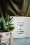 a white box with writing on it next to a plant
