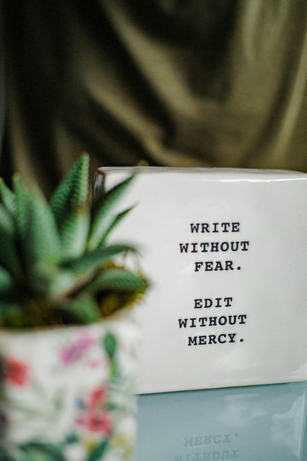 a white box with writing on it next to a plant