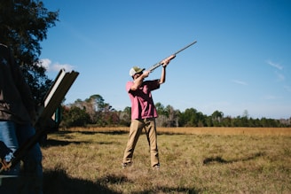 a man holding a rifle while standing in a field