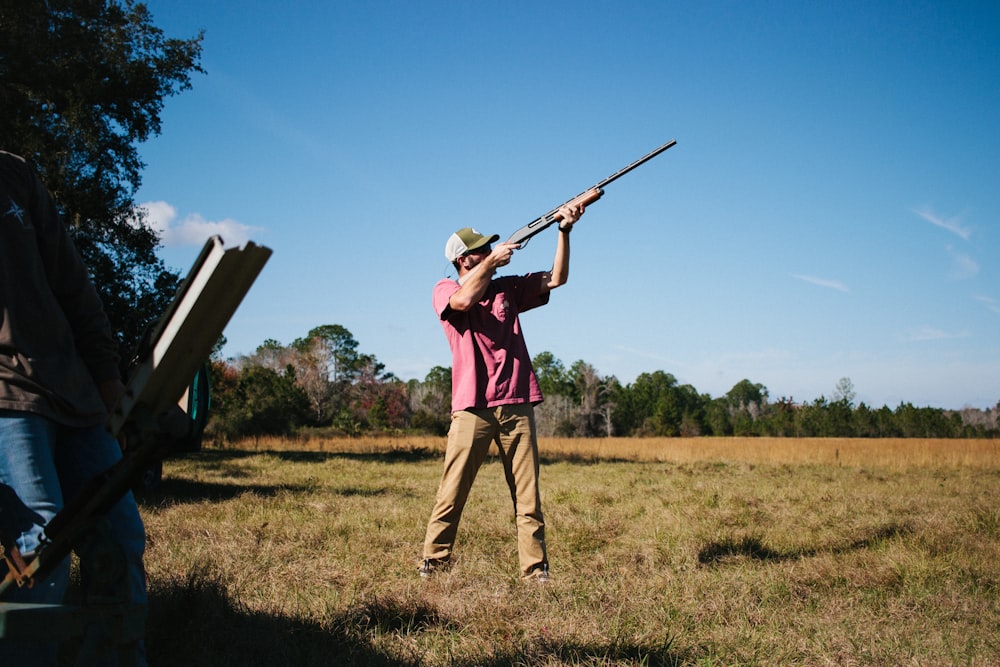 a man holding a rifle while standing in a field