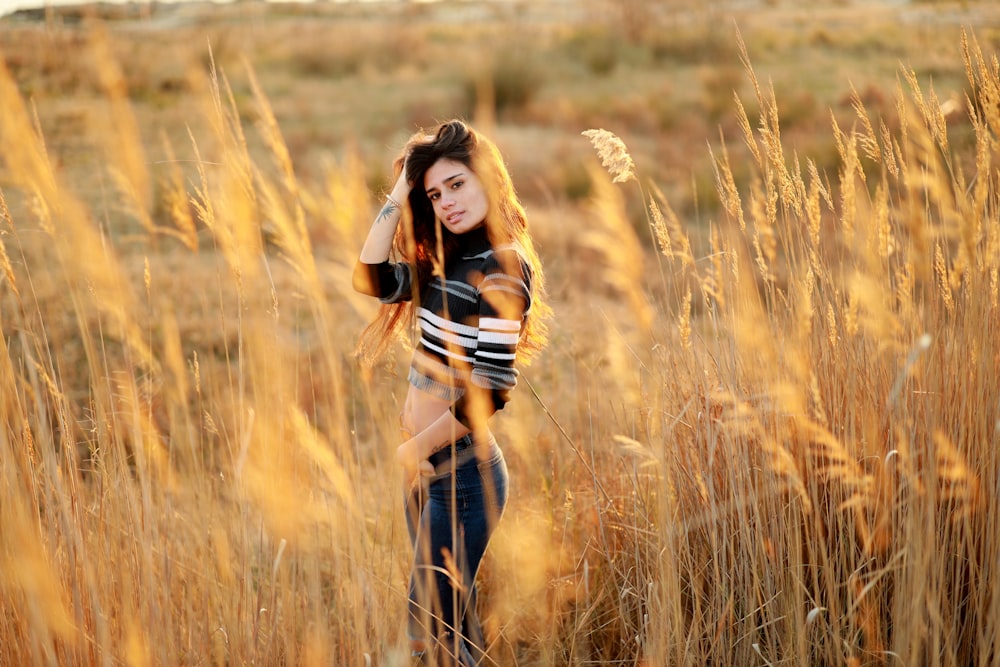 woman standing surrounded by brown hay