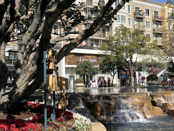 A bustling retail shopping center with vibrant storefronts and shoppers enjoying a sunny day.