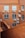 A view of an exterior wall of a building with red brick construction. Several air conditioning units are mounted on the wall below the windows, with wiring visible running along the brick surface. The shot is taken from a higher vantage point, overlooking a section of the building.