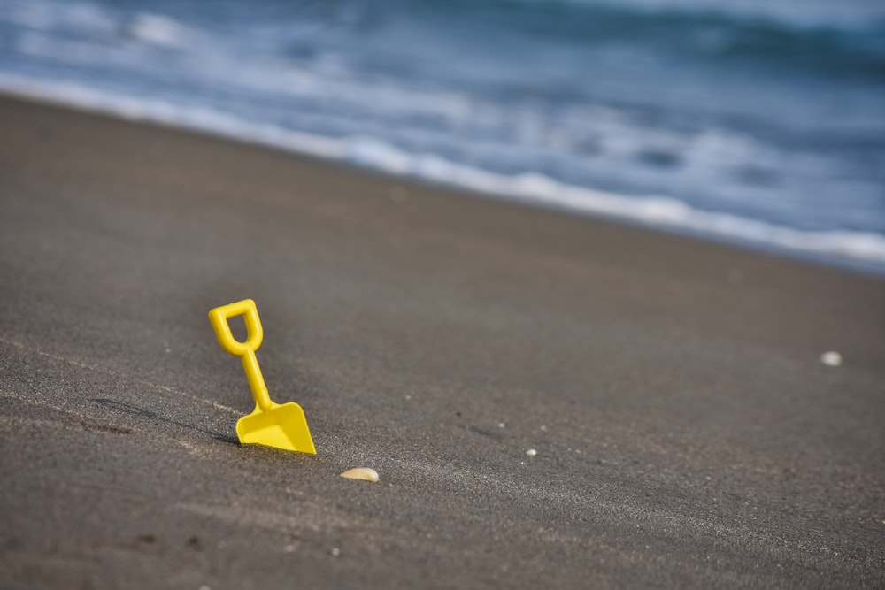 yellow plastic shovel toy on seashore