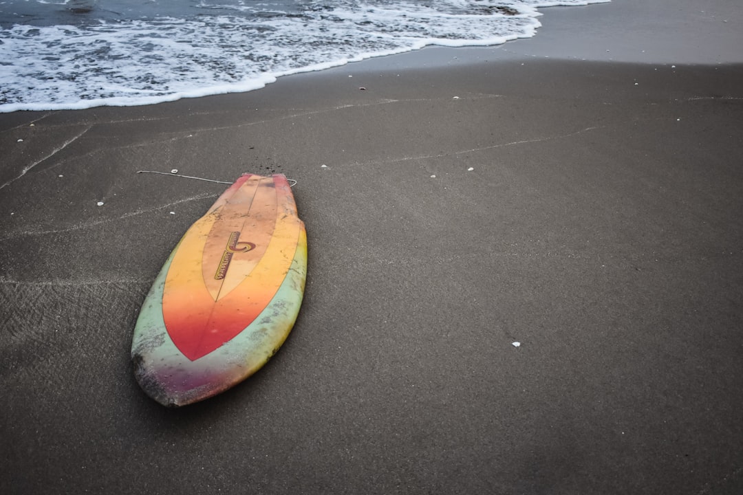 gray and orange surfboard on seashoew, 