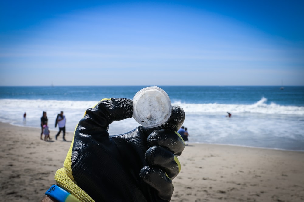 person holding round white ball near body of water during daytime