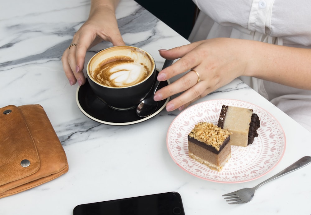 テーブルの横のカップでコーヒーを飲む女性